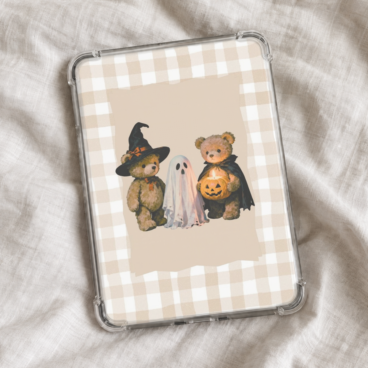 Cute vintage Halloween Kindle insert featuring two teddy bears dressed as a witch and vampire beside a little ghost, with a glowing jack-o’-lantern on a neutral beige gingham background.