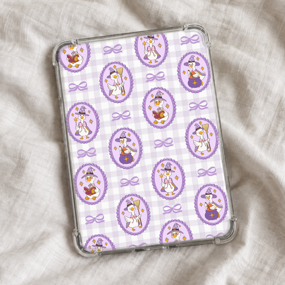 Cute Halloween Kindle insert featuring a pastel purple gingham background with whimsical witchy geese in decorative frames, purple bows, stars, broomsticks, spell books, and cauldrons.